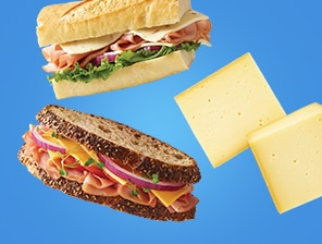 Fresh lunch meat sandwiches next to cheese wedges.