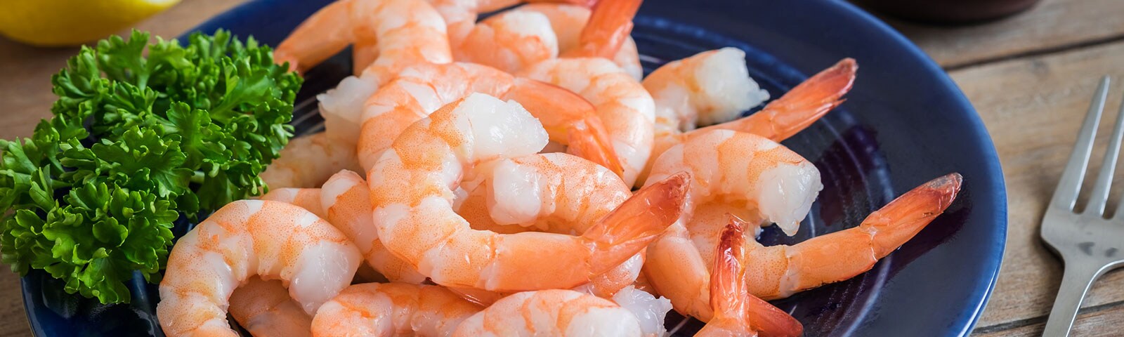 Shrimp with lettuce on a blue plate on a wooden table