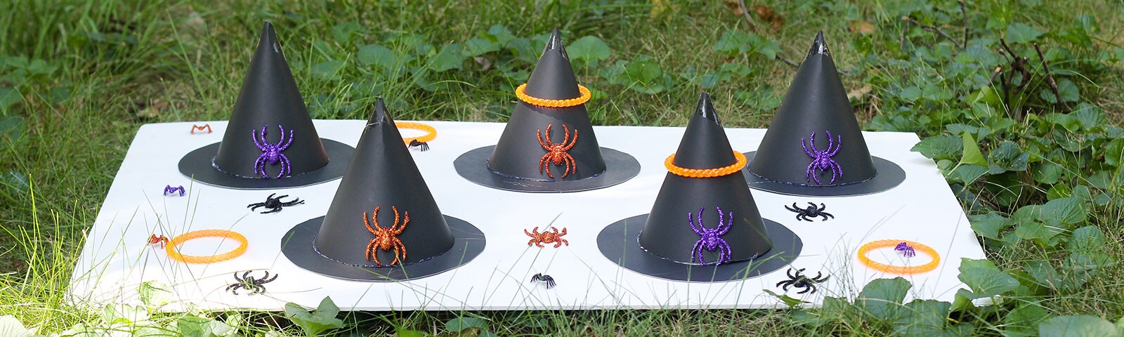 Witch Hat Ring Toss DIY game with finished witch hats and glittered plastic spiders on a lawn