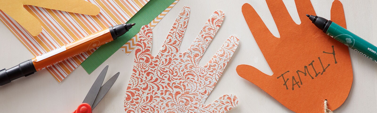 Cut-out paper hands decorated with construction paper and twine
